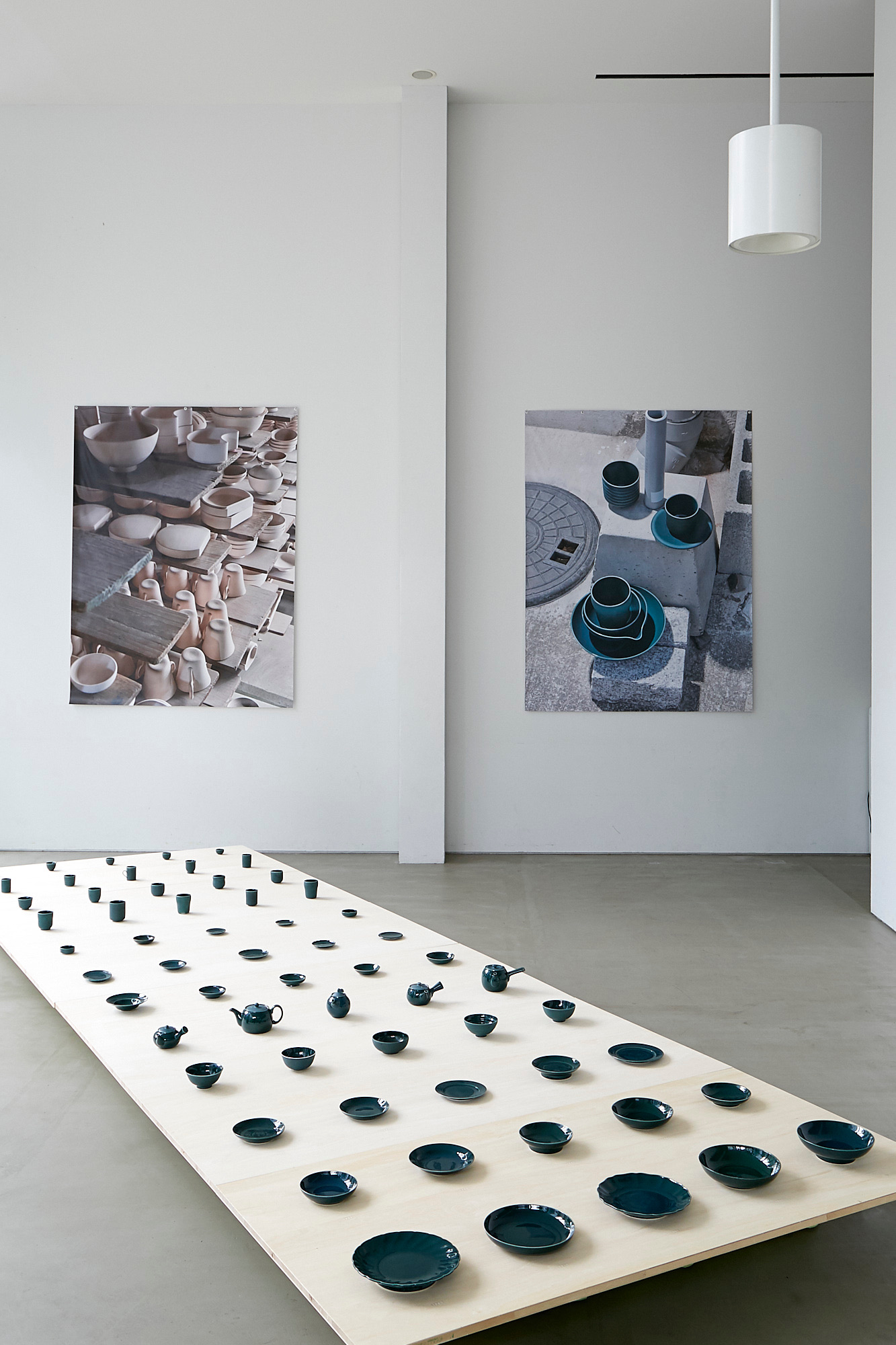 Exhibition view with green tableware on a plywood table